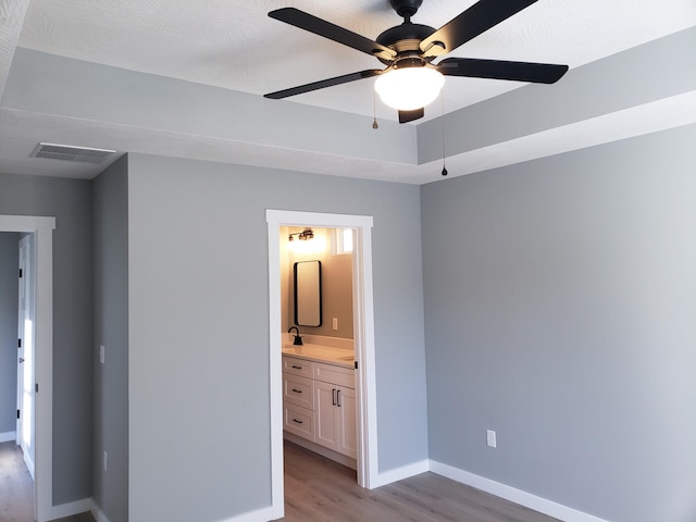 unfurnished bedroom featuring light wood finished floors, baseboards, visible vents, and connected bathroom