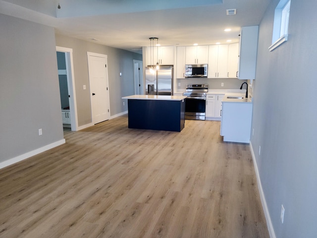 kitchen with baseboards, stainless steel appliances, a sink, and a center island