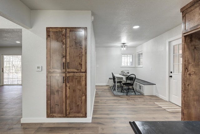 dining space featuring a textured ceiling, wood finished floors, and baseboards