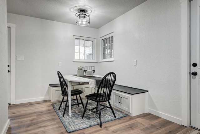 dining room featuring a textured wall, wood finished floors, and baseboards