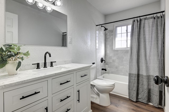 full bath with shower / bath combination with curtain, a textured wall, toilet, vanity, and wood finished floors