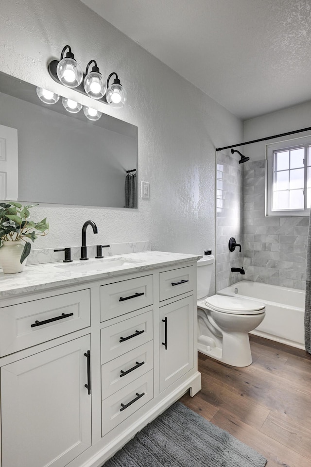 full bath with a textured wall, toilet, vanity, a textured ceiling, and wood finished floors