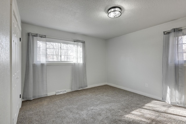 carpeted empty room with baseboards, visible vents, and a textured ceiling