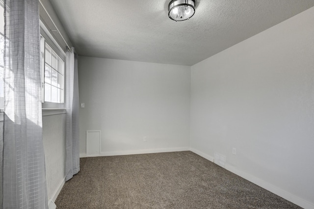 carpeted spare room with a textured ceiling and baseboards