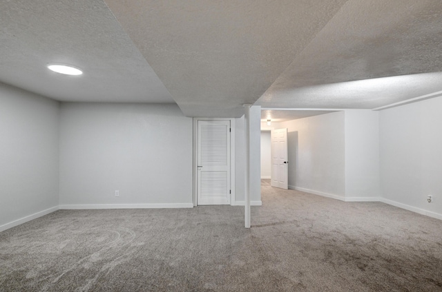 finished basement with carpet, baseboards, and a textured ceiling