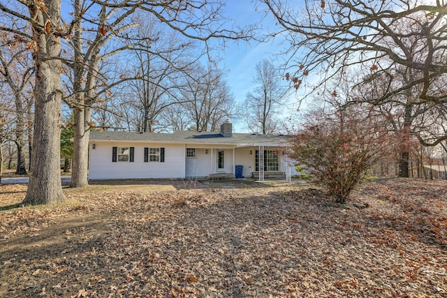 ranch-style house featuring covered porch and a chimney