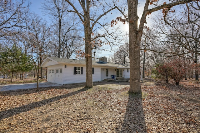 view of front of property featuring an attached garage, a chimney, and concrete driveway