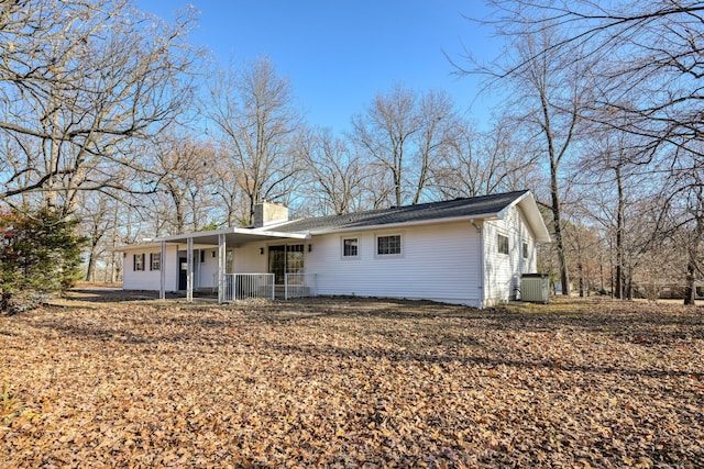 view of front of home with a porch, a chimney, and central AC unit