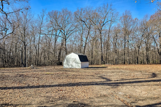 view of yard featuring a storage unit, a view of trees, and an outdoor structure