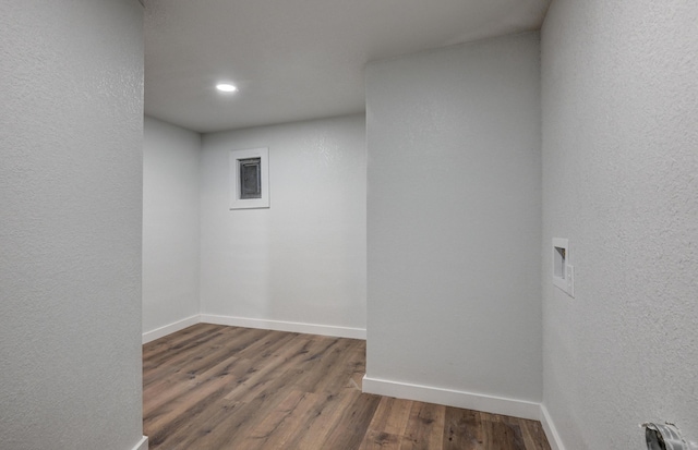 empty room featuring baseboards, wood finished floors, and a textured wall