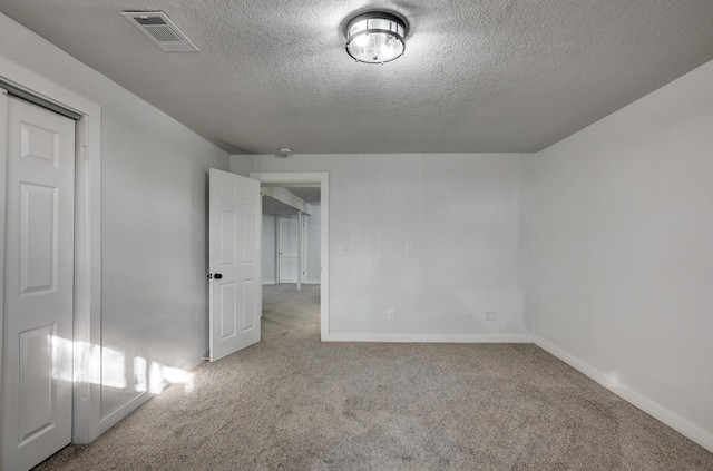 carpeted spare room featuring a textured ceiling, visible vents, and baseboards