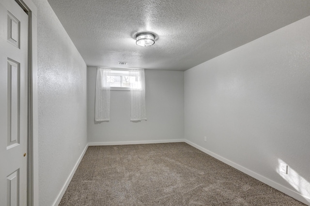 carpeted spare room featuring a textured ceiling, a textured wall, visible vents, and baseboards