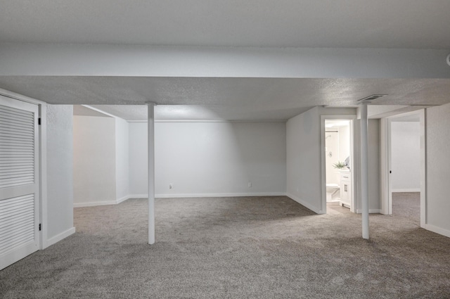 finished basement with carpet floors, baseboards, visible vents, and a textured ceiling