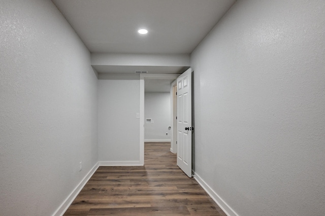 hallway featuring dark wood-type flooring, visible vents, and baseboards