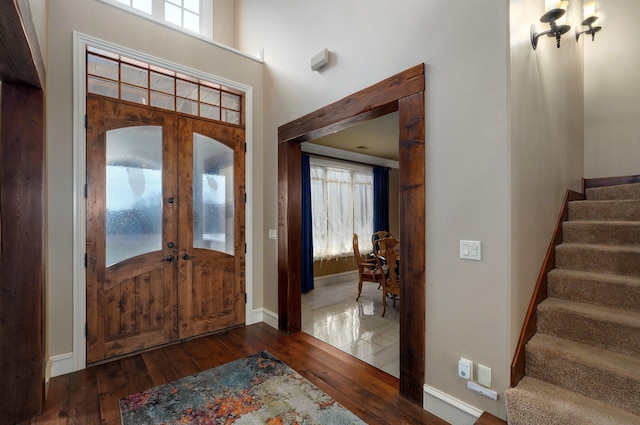 foyer entrance with baseboards, a towering ceiling, stairway, dark wood-style flooring, and french doors