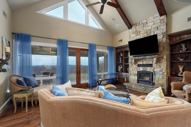 living room featuring ceiling fan, beamed ceiling, wood finished floors, a stone fireplace, and high vaulted ceiling