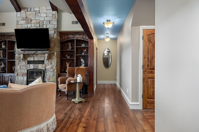 sitting room with baseboards, visible vents, wood-type flooring, a fireplace, and beam ceiling