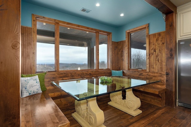 dining area featuring breakfast area, recessed lighting, visible vents, wooden walls, and hardwood / wood-style floors