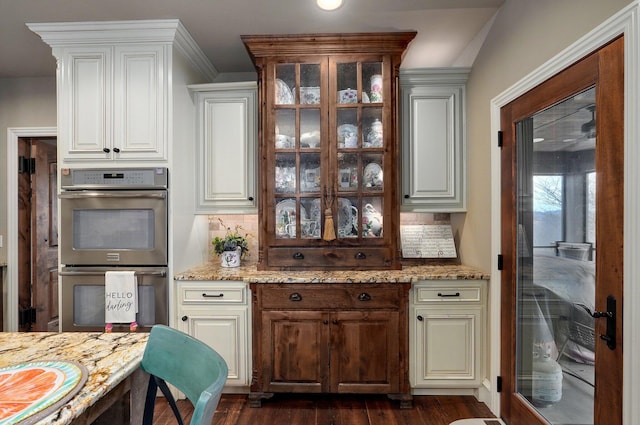 bar with stainless steel double oven, backsplash, and dark wood finished floors