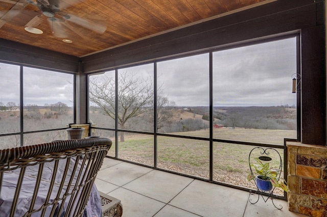 sunroom featuring wood ceiling, ceiling fan, and a rural view