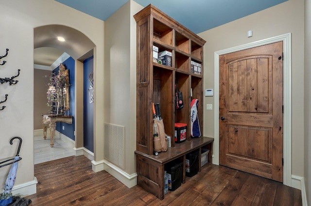 mudroom featuring hardwood / wood-style flooring, baseboards, visible vents, and arched walkways