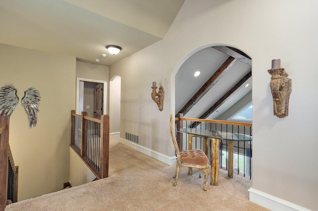 hallway featuring vaulted ceiling with beams, carpet floors, visible vents, baseboards, and an upstairs landing