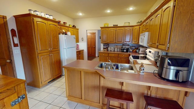 kitchen with light tile patterned floors, arched walkways, a peninsula, white appliances, and a sink