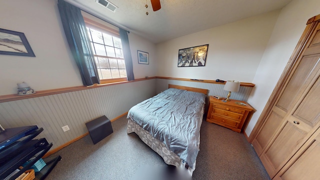 bedroom with ceiling fan, wainscoting, carpet flooring, and visible vents