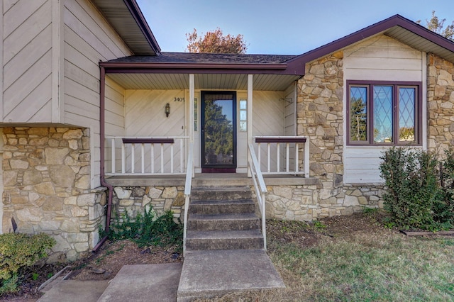 doorway to property featuring a porch and stone siding