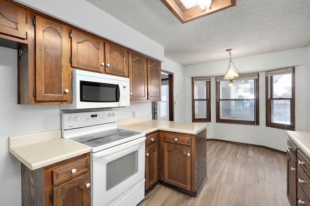 kitchen with light countertops, a textured ceiling, light wood-type flooring, white appliances, and a peninsula