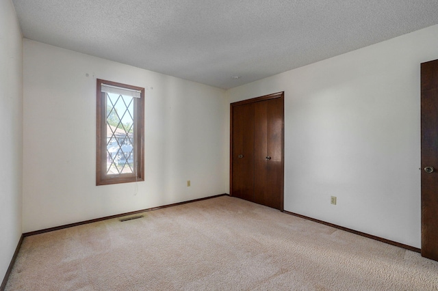 carpeted spare room featuring baseboards, visible vents, and a textured ceiling