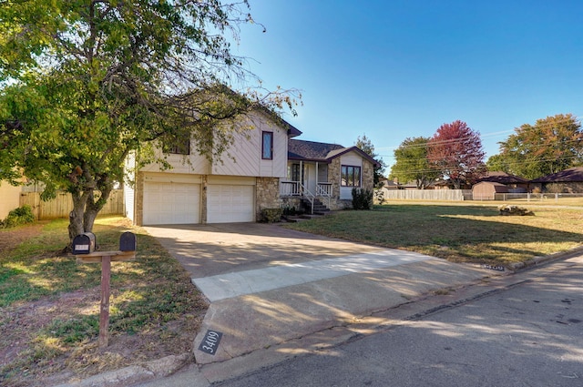 split level home with a garage, fence, a front lawn, and concrete driveway