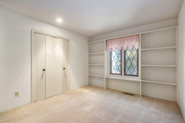 unfurnished bedroom with a textured ceiling, recessed lighting, visible vents, a closet, and carpet