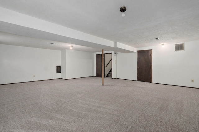 finished basement with stairs, visible vents, and light colored carpet