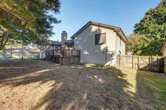 rear view of property with fence, a deck, and a lawn