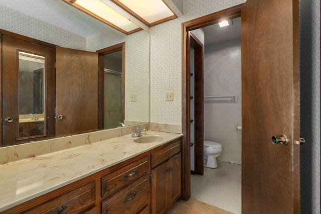 full bath featuring toilet, wallpapered walls, a shower with door, and vanity