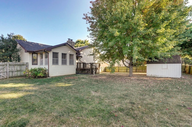 view of yard featuring a fenced backyard, a storage unit, a deck, and an outbuilding