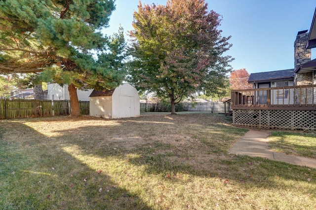 view of yard with an outbuilding, a shed, a fenced backyard, and a deck