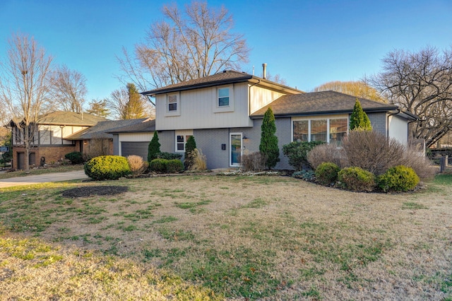 view of front of home featuring a garage, a front yard, concrete driveway, and brick siding