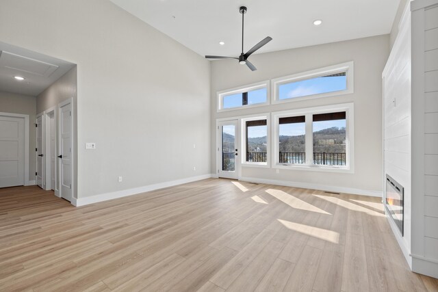 unfurnished living room featuring a fireplace, light wood-style flooring, baseboards, and ceiling fan