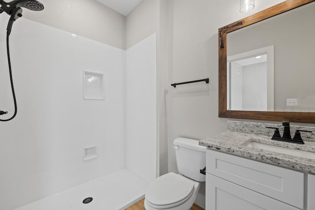 bathroom featuring a shower, vanity, and toilet