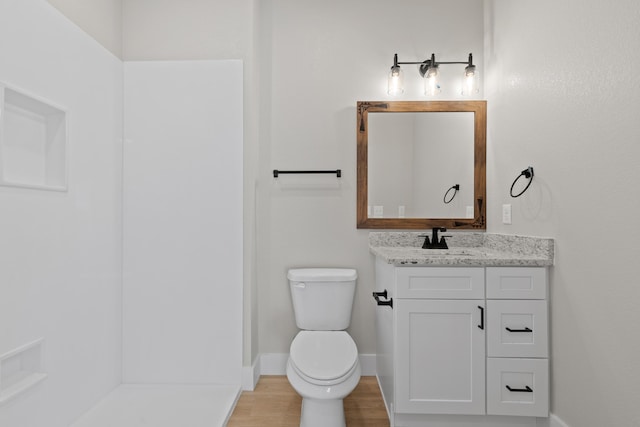 bathroom with toilet, baseboards, wood finished floors, and vanity