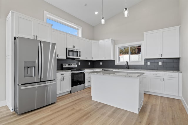 kitchen with high vaulted ceiling, appliances with stainless steel finishes, light wood-style flooring, and white cabinetry