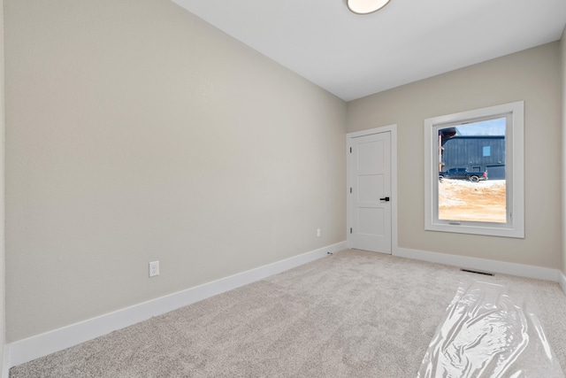 unfurnished room with light carpet, visible vents, and baseboards