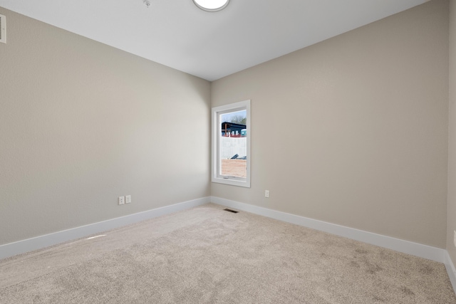 spare room with light colored carpet, visible vents, and baseboards