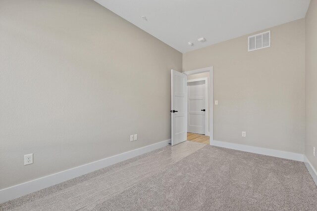 spare room featuring light carpet, visible vents, and baseboards