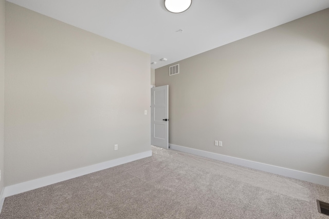 empty room featuring baseboards, visible vents, and light colored carpet