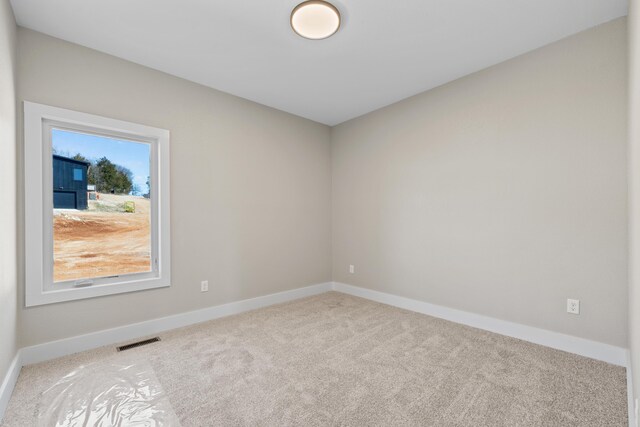 unfurnished room with carpet floors, visible vents, and baseboards