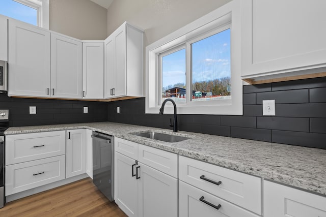 kitchen featuring tasteful backsplash, appliances with stainless steel finishes, white cabinetry, a sink, and light wood-type flooring