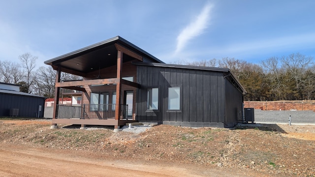 modern home featuring board and batten siding, a balcony, and central AC unit